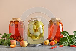 Three canned apple and cherry compote in large glass jars on gray table.