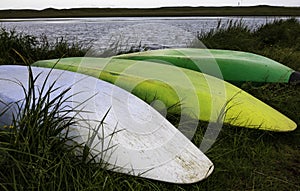 Three Canoes Lay Upside Down On Bank Of Lake