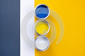 Three cans of multicolored paint on a gray-orange with a white background