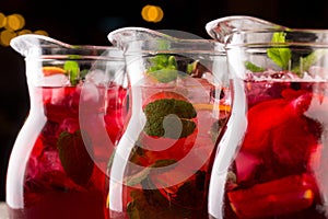 Three carafes with refreshing lemonade with glowing yellow glare on a black background.