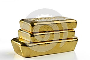 Three cast gold bars are in a pile. Isolated on a white background