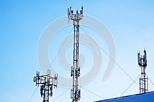 Three cell towers in the blue sky. A set of GSM and Internet transmitters and antennas. Winter