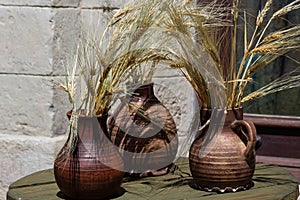 Three ceramic pots with spikelets, corn stand on the windowsill
