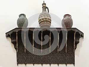 Three ceramic vases on a carved wooden shelf