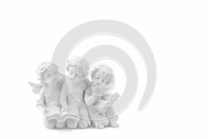 Three ceramic white angels read the book, dreaming and thinking.
