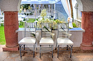 Three chairs decorated for a wedding