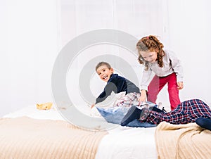 Three cheerful children with glasses jumping and playing on the bed