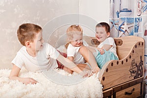 Three cheerful children play on the bed. children tickle each other bare feet at home