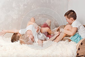 Three cheerful children play on the bed. children tickle each other bare feet at home