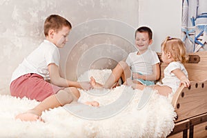 Three cheerful children play on the bed. children tickle each other bare feet at home