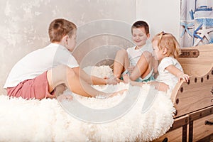 Three cheerful children play on the bed. children tickle each other bare feet at home