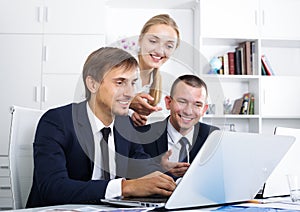 Three cheerful coworkers working in company office