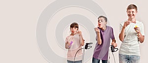 Three cheerful disabled children with Down syndrome and cerebral palsy smiling while blowing soap bubbles, standing