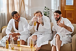 Three cheerful, diverse men in bathrobes
