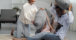 Three cheerful people Afro American family young couple with daughter little girl sitting at home in interior of living