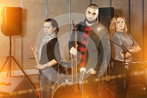 Three bandmates posing together with musical instruments in rehe