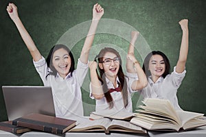 Three cheerful schoolgirls celebrate winning