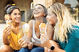 Three cheerful women eating ice cream during summer vacation in Italy