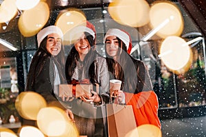 Three cheerful women spends Christmas holidays together outdoors. Conception of new year