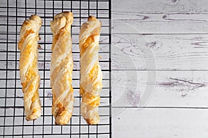 Three cheese sticks of puff pastry with spices on a baking grate with space for text