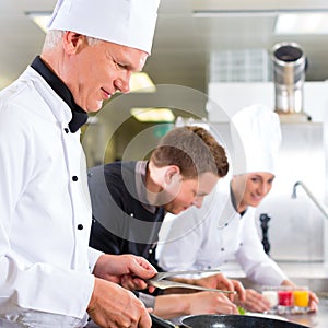 Three chefs in team in hotel or restaurant kitchen photo