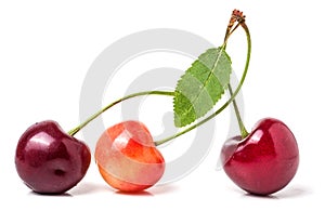 Three cherries with leaf closeup isolated on white background