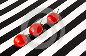 Three cherry tomatoes on a black and white striped background