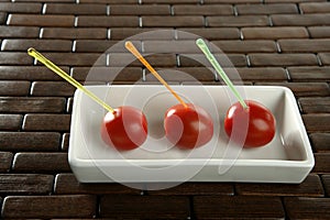 Three cherry tomatoes with color sticks