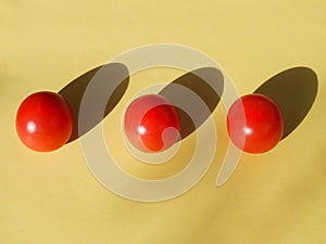 Three cherry tomatoes lie orderly on a yellow background