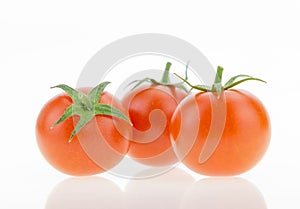 Three cherry tomatoes with reflections, on white
