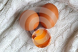 Three chicken eggs, top view, half-broken with yolk