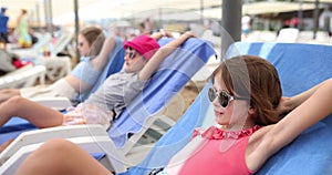 Three child girls in swimsuits and lies on sun lounger on summer day