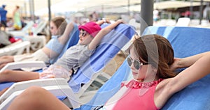 Three child girls in swimsuits and lies on sun lounger on summer day