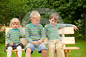 Three children on a bench in identical clothes photo