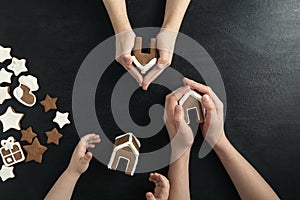 Three children with gingerbread houses in hands. Christmas seets. Top view, black background