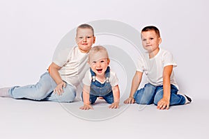 Three children in jeans and white T-shirts on white background