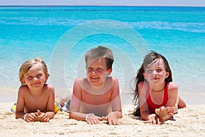 Three children lying on beach