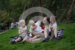 Three children and mom enjoying a picnic in summer. Togetherness concept with kids. Friendly family siblings