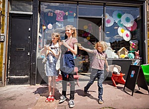 Three children outside a London toy shop, a little boy draws a toy gun