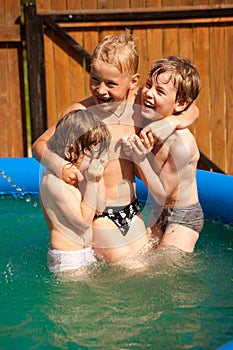 Three children play in inflatable pool