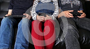 Three children playing with electronic devices - tablet, smartphone and games controller