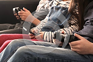 Three children playing with electronic devices - tablet, smartphone and games controller