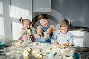 Three children prepare something from the dough.