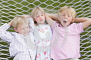 Three children relaxing and sleeping in hammock