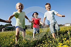 Three children running holding hands
