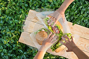 Three children`s hands to reach for the hamburgers lying on text