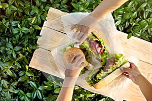 Three children`s hands to reach for the hamburgers lying on text