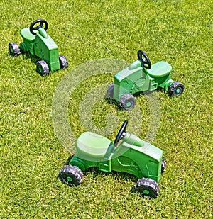 Three children`s toy farm tractors in Spring grass