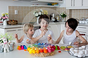 Three children, sibling brothers, painting easter eggs for decoration