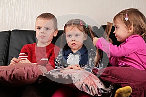 Three children on sofa watching tv